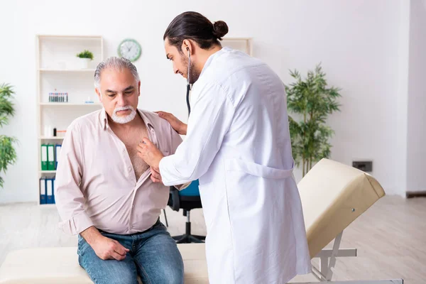 Oude man op bezoek bij jonge mannelijke arts cardioloog — Stockfoto