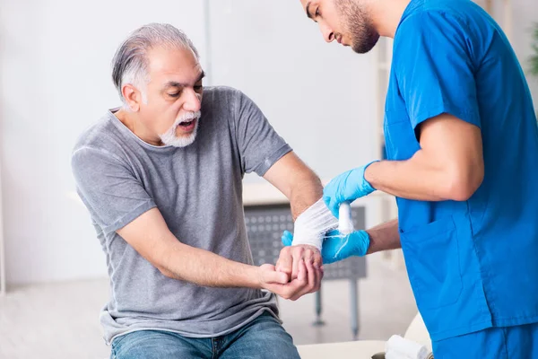 Junger Arzt und alter Patient im Erste-Hilfe-Konzept — Stockfoto