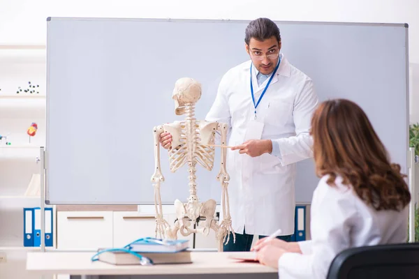 Ung manlig lärare läkare, skelett och kvinnlig student i cl — Stockfoto
