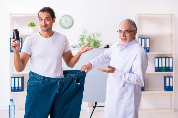 Doctor dietician and happy patient wearing large trousers — Stok fotoğraf