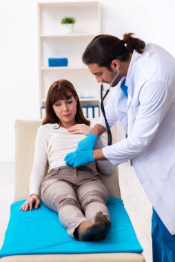 Yaralı genç kadın genç erkek doktoru ziyaret ediyor.