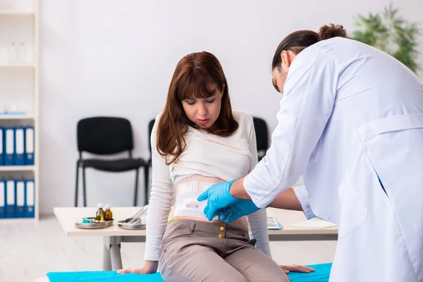 Mulher jovem ferida visitando jovem médico masculino — Fotografia de Stock