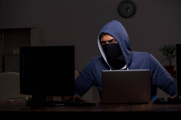 Male hacker hacking security firewall late in office