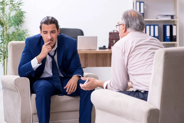 Young man visiting old male doctor psychologist — Stock Photo, Image