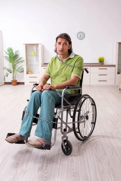 Jeune homme invalide en fauteuil roulant souffrant à la maison — Photo