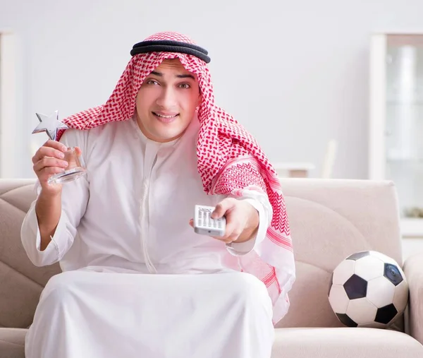 Hombre árabe joven viendo fútbol sentado en el sofá — Foto de Stock