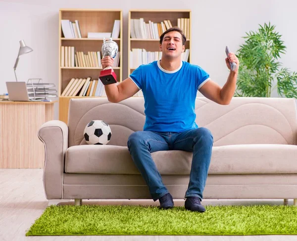 A férfi otthon focit néz, a kanapén ül. — Stock Fotó