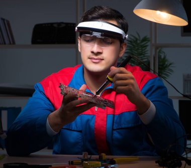 Bilgisayar uzmanı gece geç saatlerde bilgisayarı tamir ediyor.