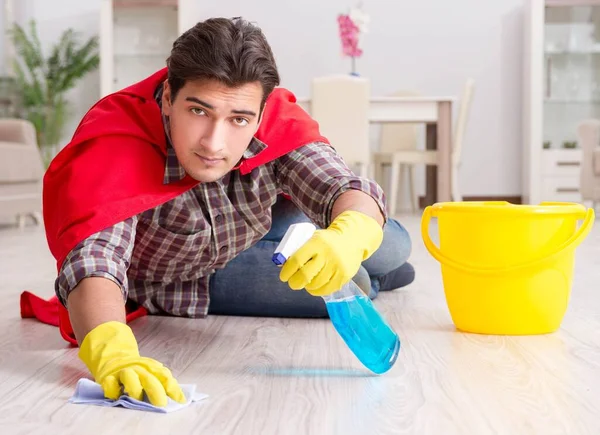 Super herói marido limpeza chão em casa — Fotografia de Stock