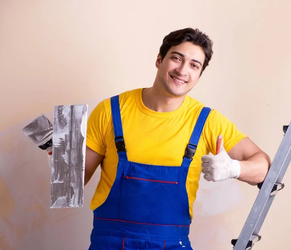 Empleado joven contratista aplicando yeso en la pared — Foto de Stock