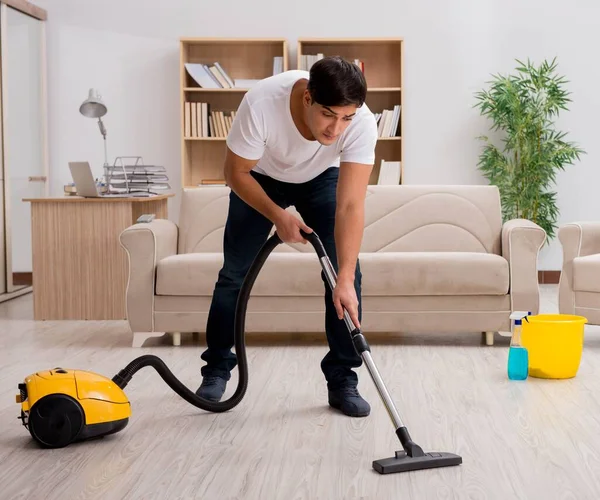 Mężczyzna sprzątanie domu z odkurzacza — Zdjęcie stockowe