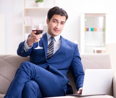 İş adamı evde oturmuş şarap içiyor.