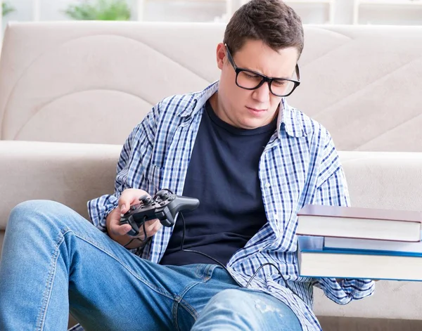 Jeune étudiant essayant d'équilibrer étudier et jouer à des jeux — Photo