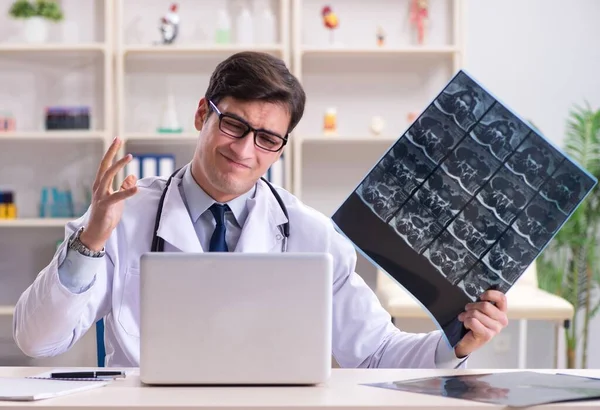 Young doctor looking at x-ray images in clinic — Stock Photo, Image