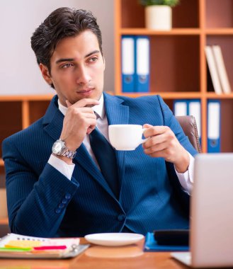 Genç yakışıklı işadamı ofiste çalışıyor.