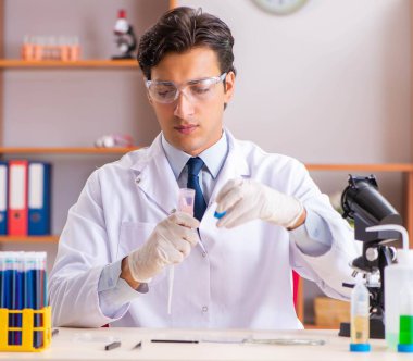 Genç yakışıklı biyokimyacı laboratuvarda çalışıyor.