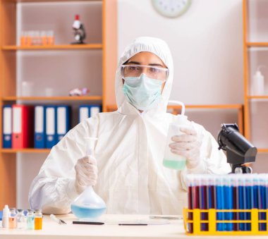 Laboratuvarda çalışan koruyucu elbise giyen genç bir biyokimyacı.