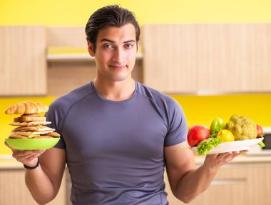 Sağlıklı ve sağlıksız yemek arasında zor bir seçim yapan bir adam.