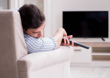 Genç adam evde televizyon izliyor.