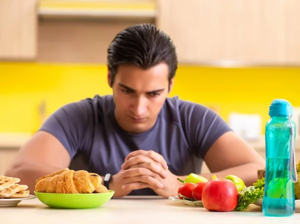 Man having hard choice between healthy and unhealthy food