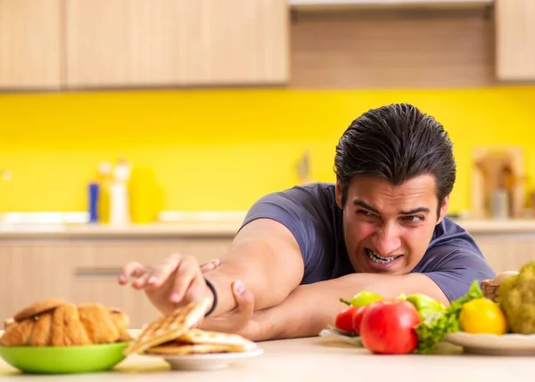 Hombre que tiene difícil elección entre la comida sana y no saludable — Foto de Stock