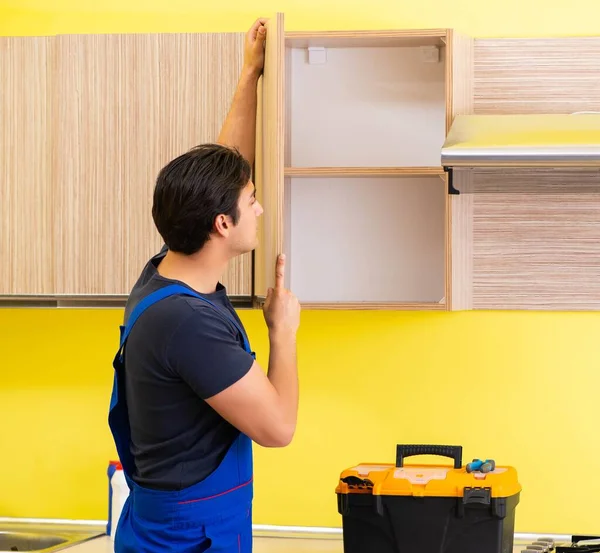 Joven contratista de servicio ensamblando muebles de cocina —  Fotos de Stock