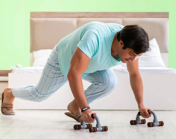 Jongeman in pyjama doet 's ochtends oefeningen — Stockfoto