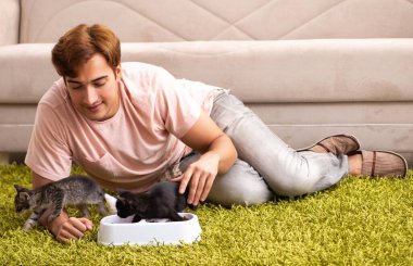 Genç adam evde kedi yavrusuyla oynuyor.