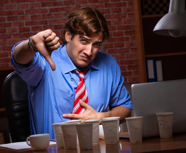 Ung anställd dricker kaffe och jobbar nattskift — Stockfoto