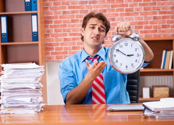 Jovem funcionário com excesso de trabalho sentado no escritório — Fotografia de Stock