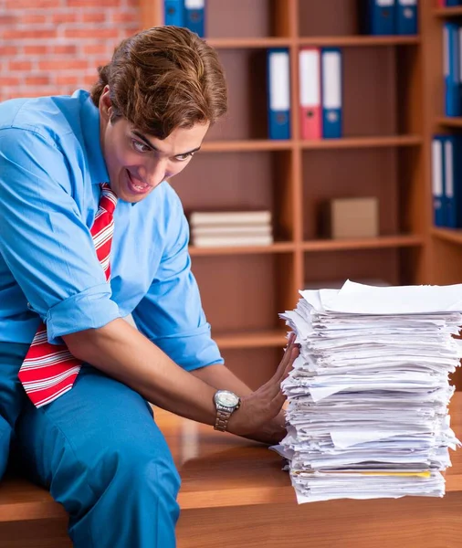 Jeune employé ayant un travail excessif assis au bureau — Photo