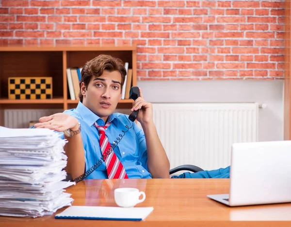Ofiste aşırı işi olan genç bir çalışan oturuyor. — Stok fotoğraf
