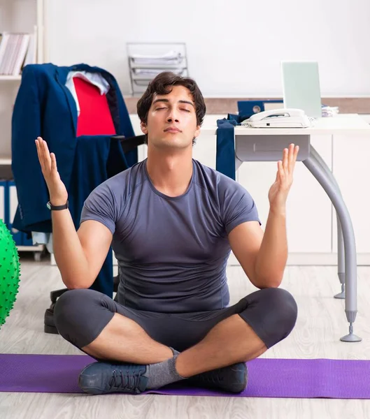 Young male employee exercising in the office — Stock Photo, Image