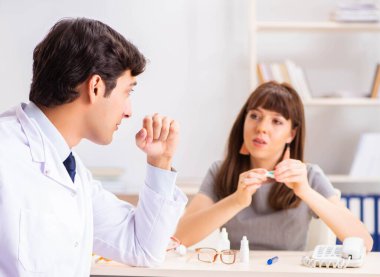 Genç bir kadın, erkek doktor göz doktorunu hastanede ziyaret ediyor.