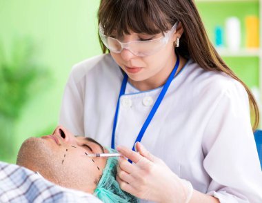 Estetik cerrah insan yüzü ameliyatına hazırlanıyor.