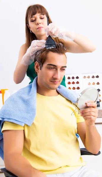 Cabeleireiro mulher aplicando tintura para o cabelo do homem — Fotografia de Stock