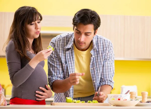 Hombre y mujer embarazada preparando ensalada en la cocina —  Fotos de Stock