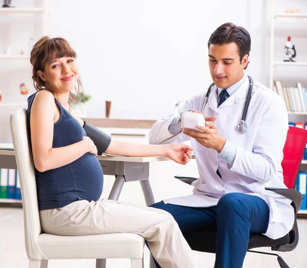 Young doctor checking pregnant womans blood pressure — Stock Photo, Image