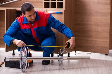 Genç yakışıklı erkek marangoz içeride çalışıyor.