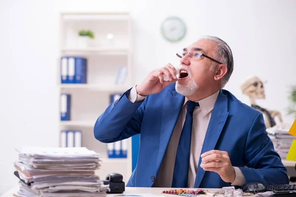 Viejo empleado enfermo trabajando horas extras en la oficina — Foto de Stock