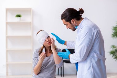 Genç baş yaralı kadın genç erkek doktoru ziyaret ediyor.
