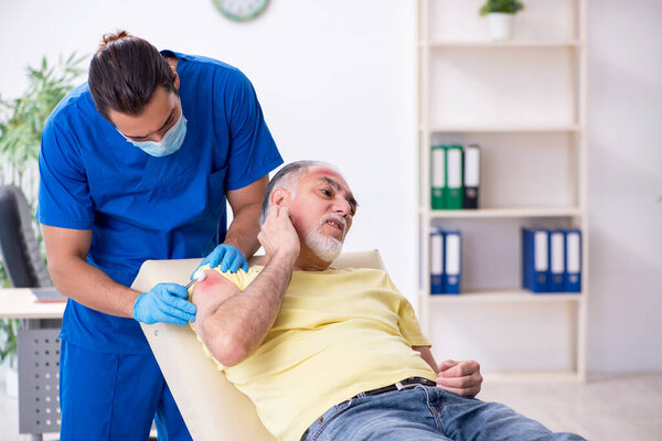 Injured old man visiting young male doctor traumatologist