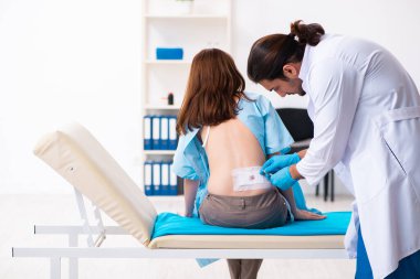 Yaralı genç kadın genç erkek doktoru ziyaret ediyor.