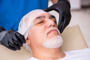 Yaşlı adam estetik ameliyat için erkek doktoru ziyaret ediyor.