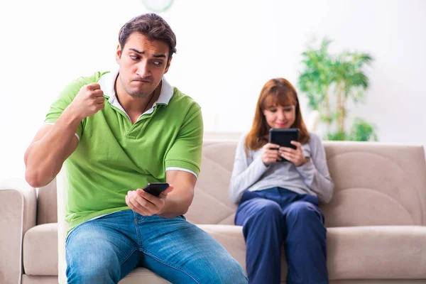 Young couple in gadget dependency concept — Stock Photo, Image