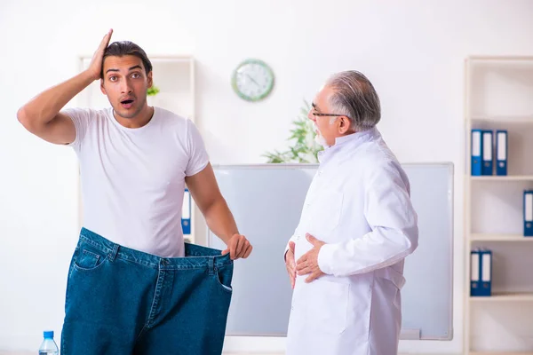 Doctor dietician and happy patient wearing large trousers — 스톡 사진