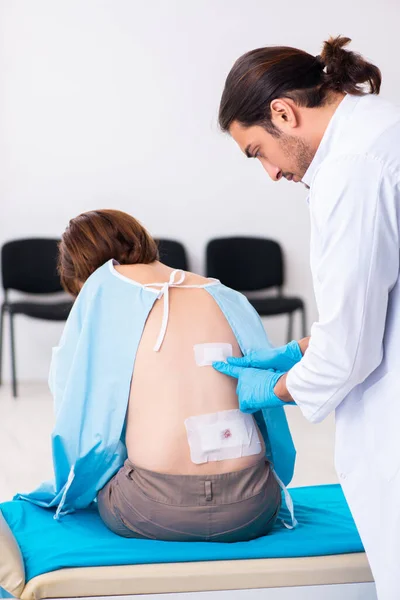 Yaralı genç kadın genç erkek doktoru ziyaret ediyor. — Stok fotoğraf