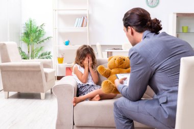Çocuk psikoloğu küçük bir kıza bakıyor