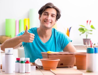 Sınıfta çömlek dekorasyonu yapan genç bir adam.