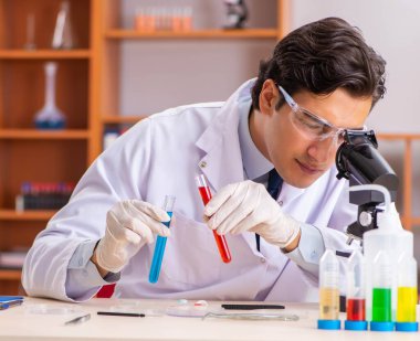 Genç yakışıklı biyokimyacı laboratuvarda çalışıyor.